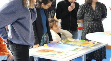 Five people stand and one kneels behind a table covered with informative posters from the hubREN project
