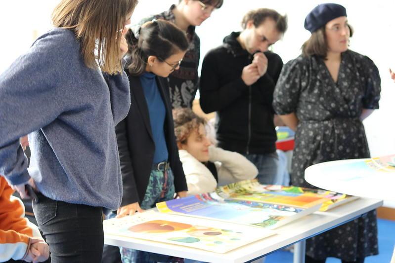 Five people stand and one kneels behind a table covered with informative posters from the hubREN project