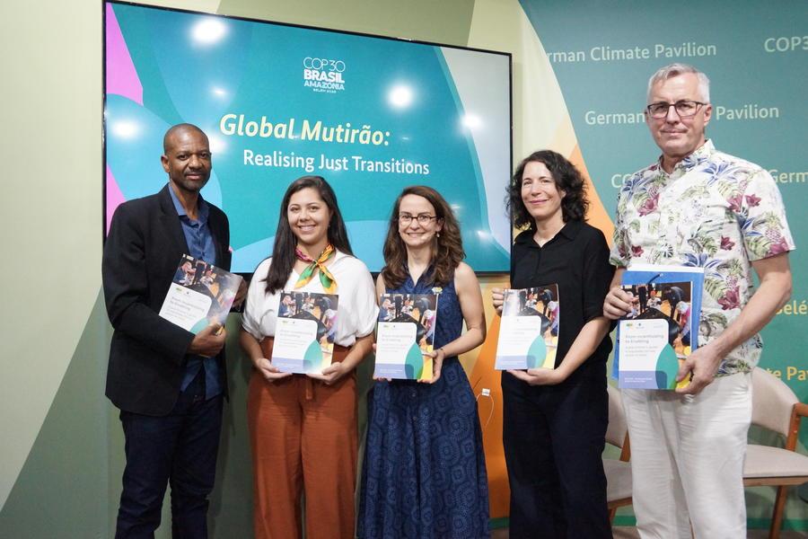 Five speakers holding the INCLUDE guidebook in front of a TV screen