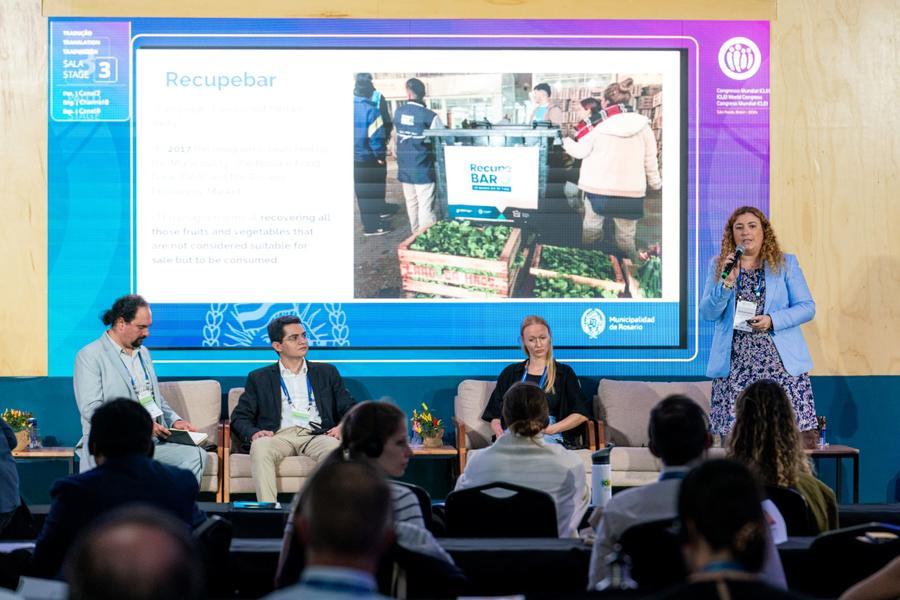 Four panellists presenting to a group of people wearing headphones
